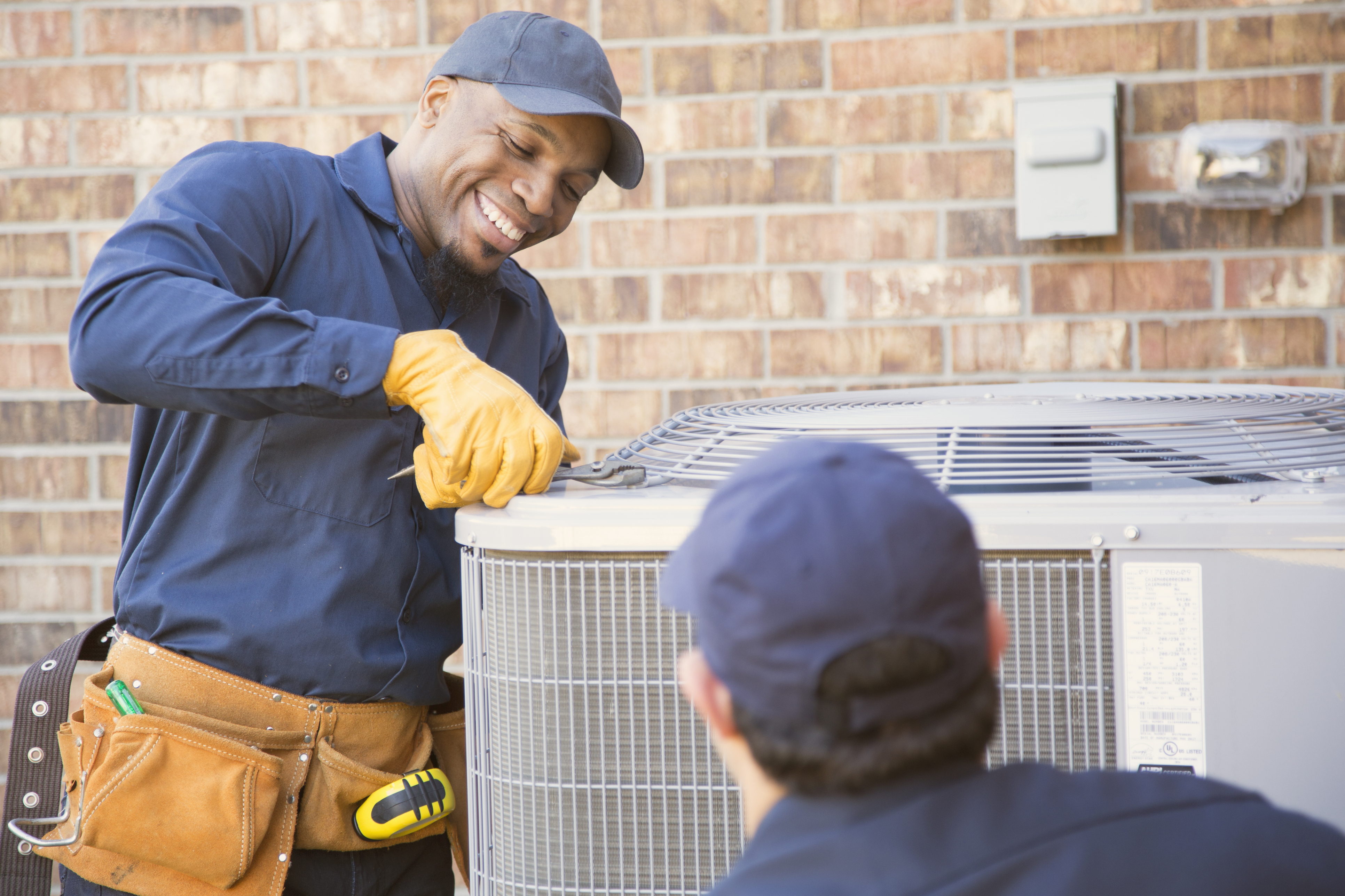 Multi-ethnic team of blue collar air conditioner repairmen in Lexington, KY at work